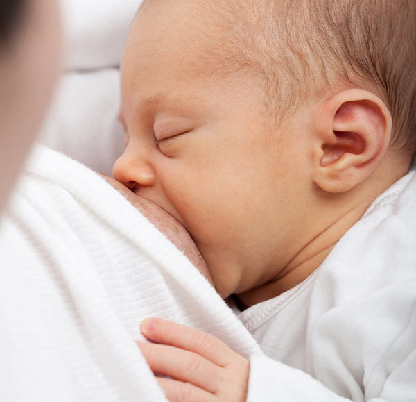 Bebê mamando, indicando que amamentação não faz o cabelo cair